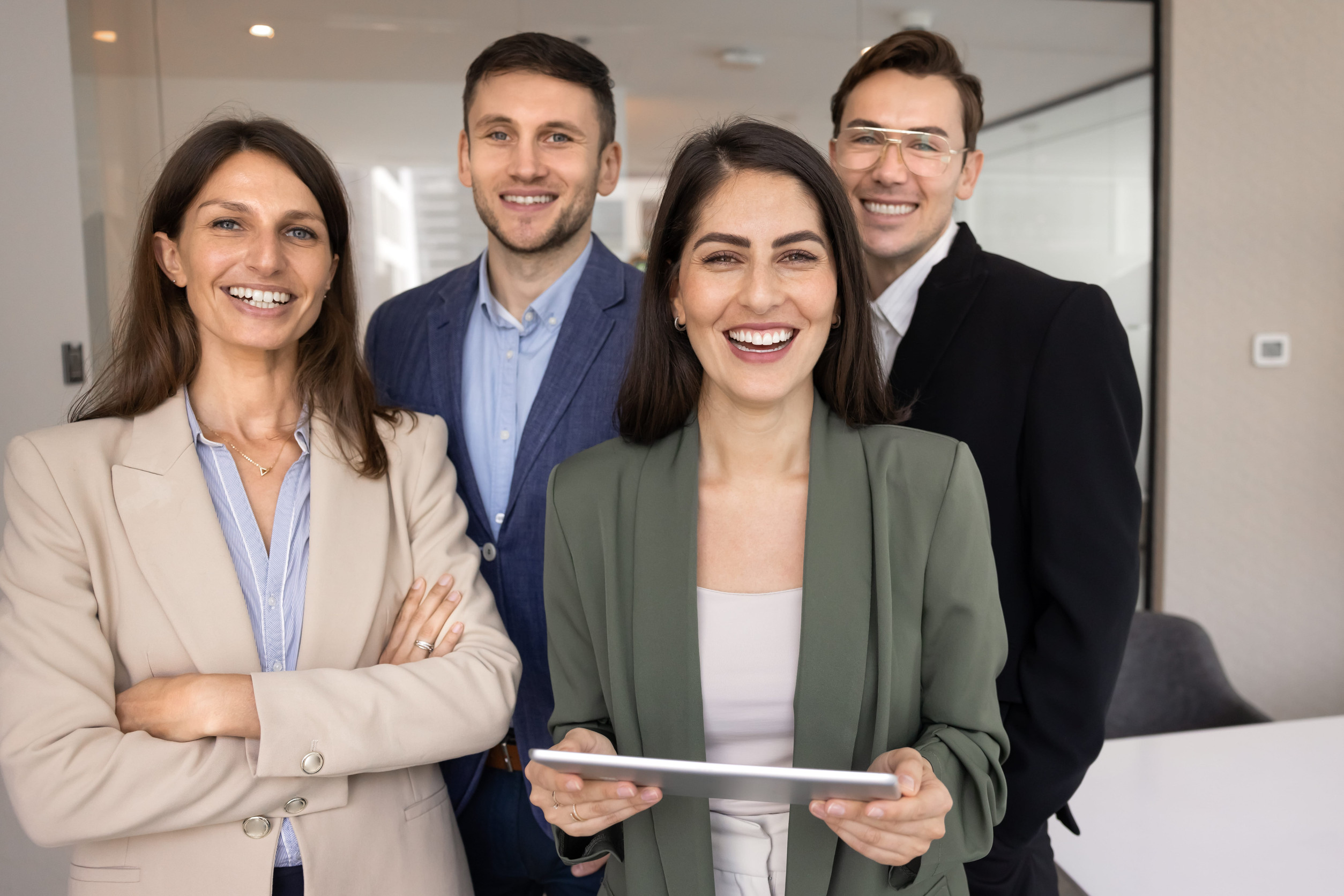 First Time Home Buyer Georgia: Business team of happy attractive young business professional men and women standing together, looking at camera with toothy smiles, posing in office. Successful company staff profile portrait