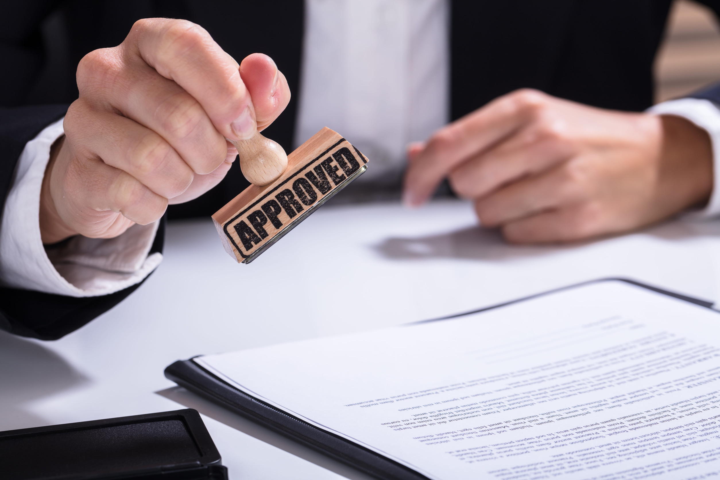 First Time Home Buyer Georgia: Close-up Of Person Hands Using Stamper On Document With The Text Approved
